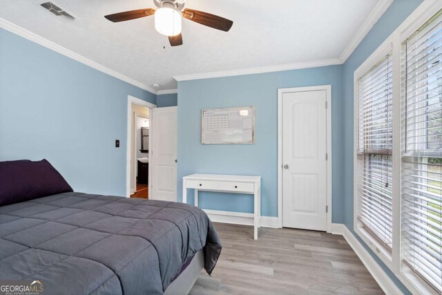 bedroom featuring baseboards, visible vents, crown molding, and wood finished floors