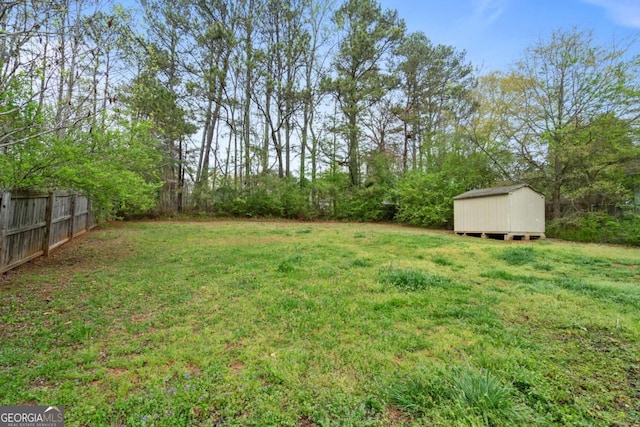 view of yard with an outbuilding, fence, and a storage shed