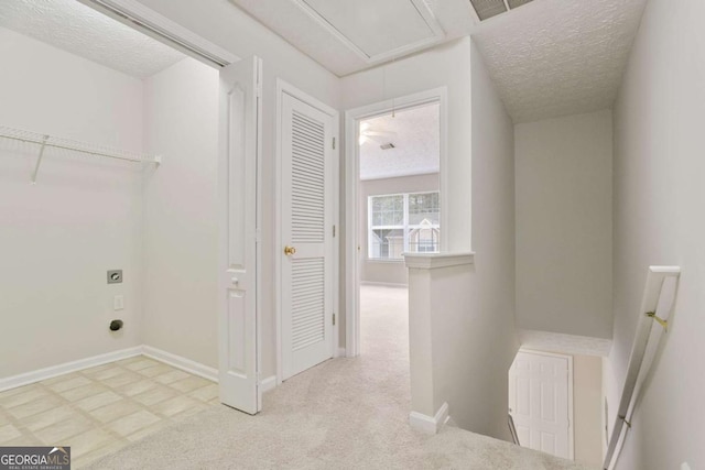 laundry room featuring electric dryer hookup, attic access, laundry area, and a textured ceiling