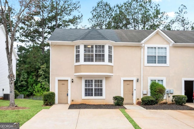 view of property with stucco siding, central air condition unit, and a front lawn
