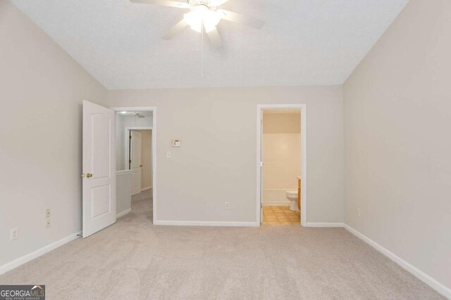 unfurnished bedroom featuring carpet flooring, baseboards, a textured ceiling, a ceiling fan, and ensuite bathroom