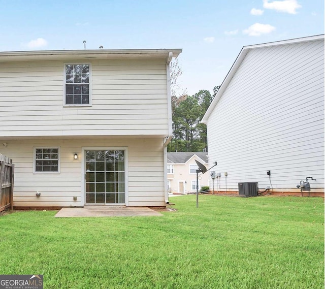 rear view of property with central air condition unit and a yard