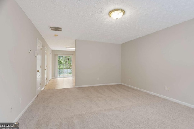 spare room featuring light colored carpet, visible vents, and baseboards