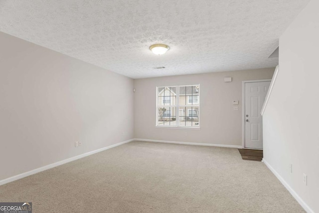 unfurnished room with carpet, baseboards, and a textured ceiling