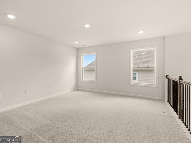 spare room with baseboards, recessed lighting, and light carpet