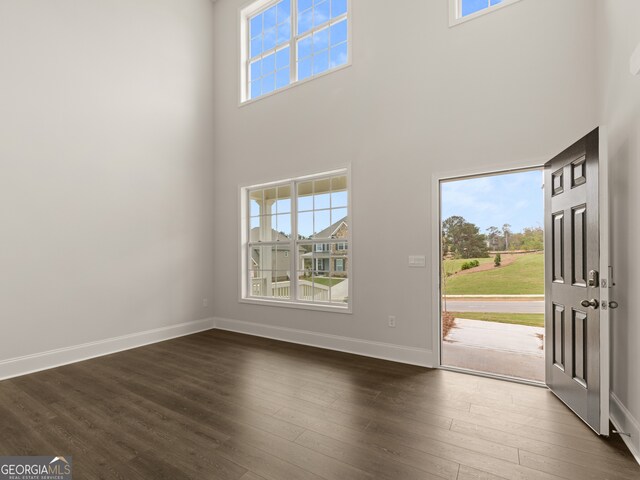 entryway with dark wood finished floors, baseboards, plenty of natural light, and a towering ceiling