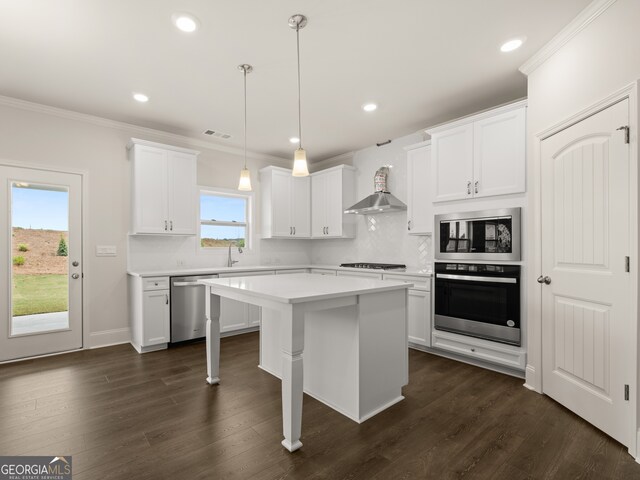 kitchen featuring light countertops, appliances with stainless steel finishes, crown molding, and wall chimney exhaust hood