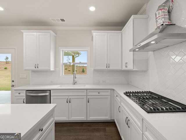 kitchen with visible vents, ornamental molding, stainless steel appliances, wall chimney exhaust hood, and a sink