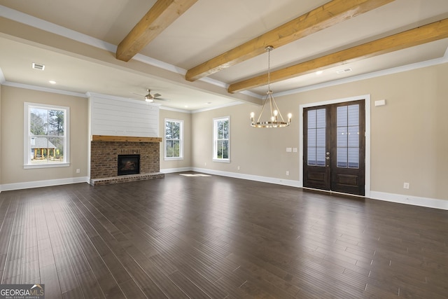 unfurnished living room with visible vents, a brick fireplace, dark wood finished floors, beam ceiling, and ceiling fan with notable chandelier