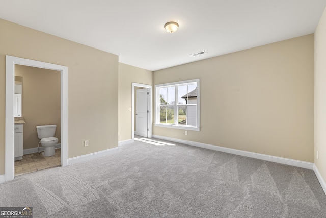unfurnished bedroom with carpet floors, ensuite bathroom, baseboards, and visible vents