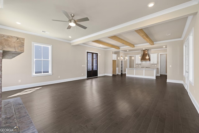 unfurnished living room featuring ceiling fan with notable chandelier, baseboards, beamed ceiling, and dark wood finished floors
