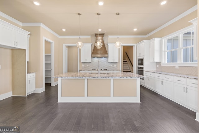 kitchen with white cabinets, custom exhaust hood, ornamental molding, stainless steel oven, and built in microwave