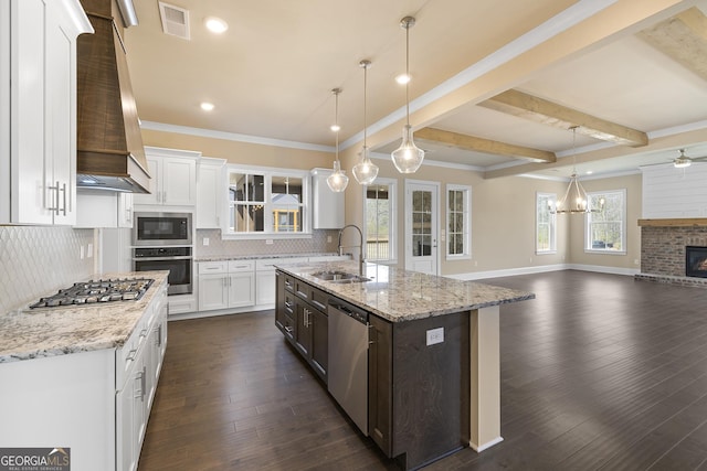 kitchen featuring a sink, wall chimney exhaust hood, stainless steel appliances, visible vents, and decorative backsplash