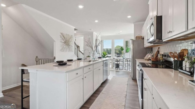 kitchen featuring a kitchen bar, tasteful backsplash, stainless steel appliances, a center island with sink, and a sink