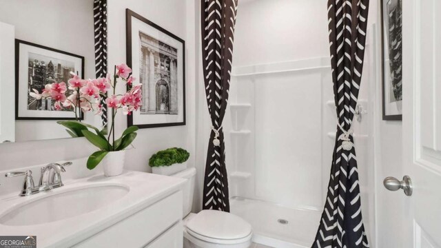 full bath with toilet, vanity, and a shower stall