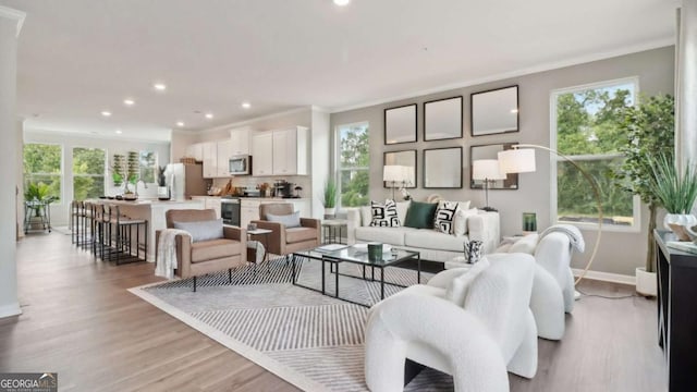 living room with baseboards, recessed lighting, light wood-style floors, and ornamental molding