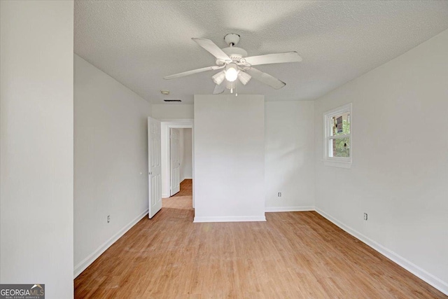empty room featuring light wood-style flooring, baseboards, a ceiling fan, and a textured ceiling