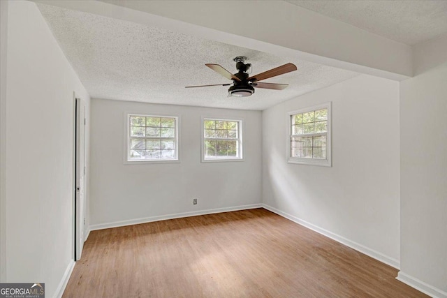 spare room featuring ceiling fan, baseboards, light wood-style floors, and a textured ceiling