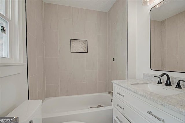 bathroom featuring toilet, vanity, and bathtub / shower combination