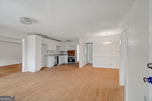 unfurnished living room featuring light wood-type flooring, a textured ceiling, and baseboards