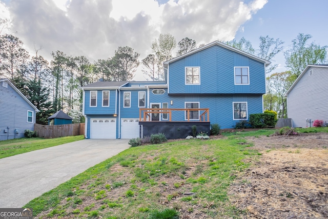 split level home featuring a front lawn, fence, driveway, and an attached garage