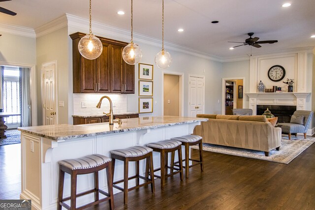 2 Palmer Dr NW, Rome, GA 30165 - kitchen featuring ceiling fan, ornamental molding, dark wood-style floors, a kitchen island with sink, and a breakfast bar