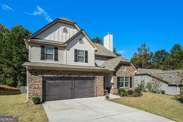 view of front of house featuring a garage, board and batten siding, a front yard, and stone siding