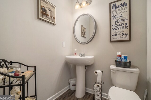 bathroom with toilet, baseboards, and wood finished floors