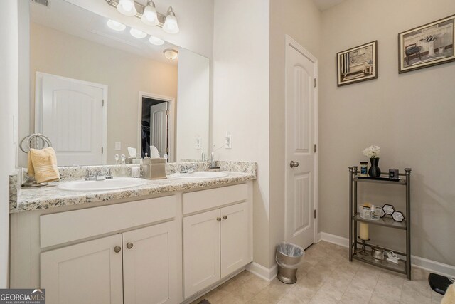 full bathroom with double vanity, a sink, baseboards, and tile patterned floors