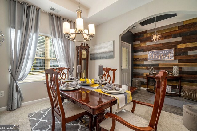 dining room with visible vents, arched walkways, baseboards, a notable chandelier, and wooden walls