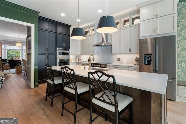 2630 Milford Ln, Alpharetta, GA 30009 - kitchen with appliances with stainless steel finishes, a center island with sink, light countertops, glass insert cabinets, and light wood-style flooring