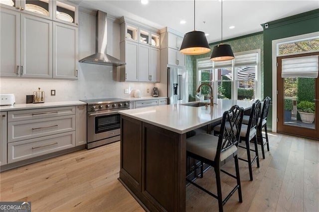 2630 Milford Ln, Alpharetta, GA 30009 - kitchen featuring wall chimney range hood, high end appliances, light countertops, light wood finished floors, and a center island with sink