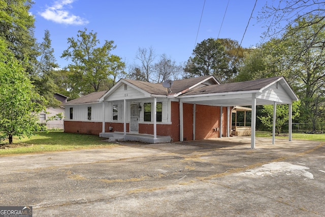 ranch-style house with driveway, an attached carport, a front lawn, and brick siding