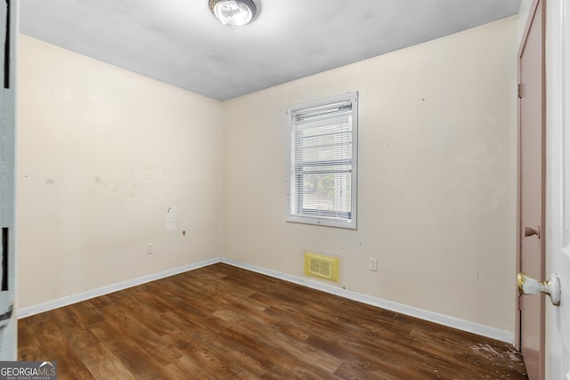 spare room featuring visible vents, baseboards, and wood finished floors