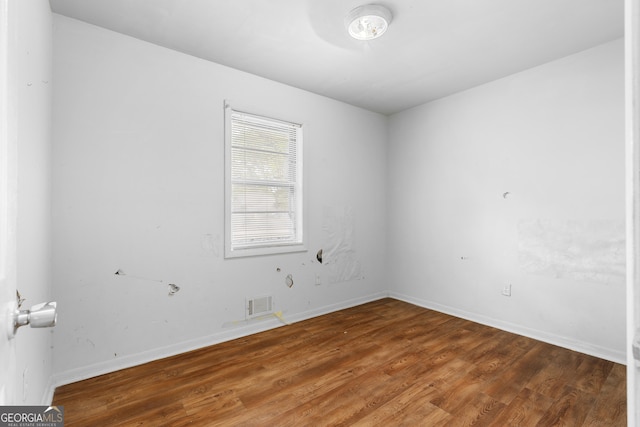 unfurnished room featuring visible vents, baseboards, and wood finished floors