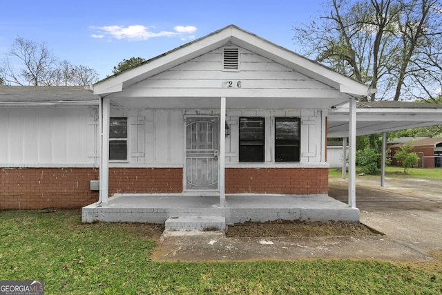 view of front of house featuring concrete driveway, a carport, brick siding, and covered porch