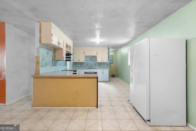 kitchen with tasteful backsplash, white fridge with ice dispenser, a sink, light countertops, and a peninsula