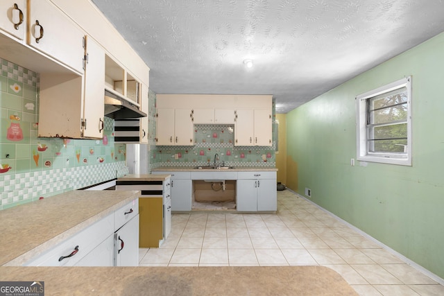 kitchen with light countertops, tasteful backsplash, light tile patterned floors, and a sink