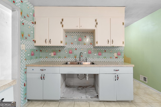 kitchen featuring light countertops, decorative backsplash, and a sink