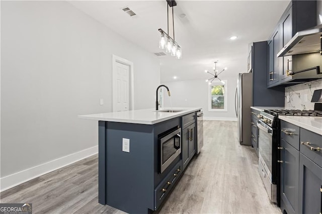 358 Roy St SW, Atlanta, GA 30310 - kitchen with appliances with stainless steel finishes, wall chimney range hood, a sink, light wood-type flooring, and an island with sink