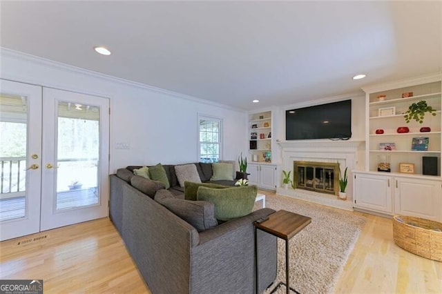 3811 Valley Green Dr, Marietta, GA 30068 - living room with ornamental molding, light wood-type flooring, french doors, a glass covered fireplace, and built in shelves