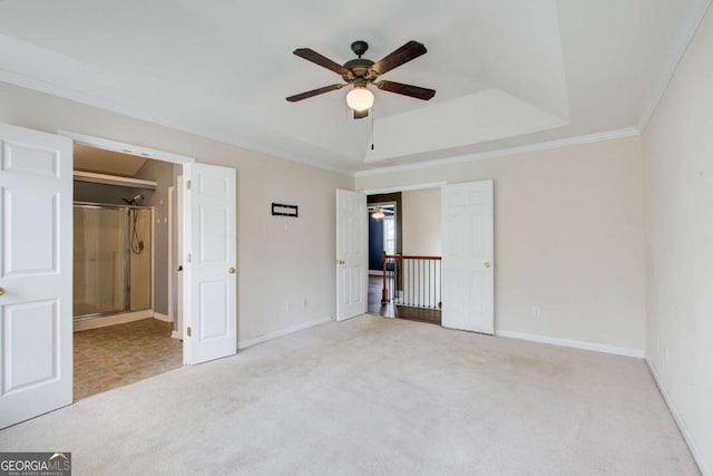 unfurnished bedroom with carpet flooring, a tray ceiling, baseboards, connected bathroom, and ornamental molding