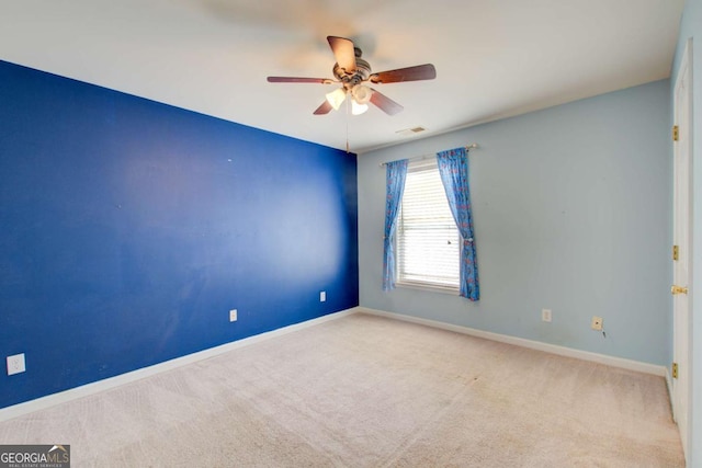carpeted empty room with visible vents, a ceiling fan, and baseboards