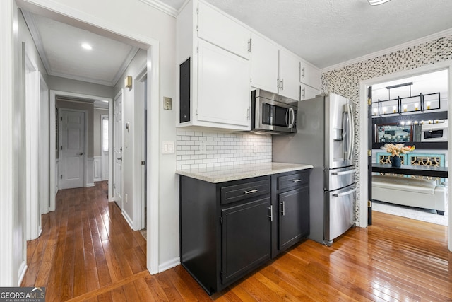 292 Old Rosser Rd, Stone Mountain, GA 30087 - kitchen with wood-type flooring, ornamental molding, decorative backsplash, white cabinets, and stainless steel appliances