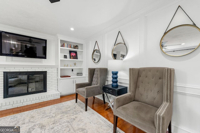 292 Old Rosser Rd, Stone Mountain, GA 30087 - living area with crown molding, a fireplace, built in shelves, wood finished floors, and a decorative wall