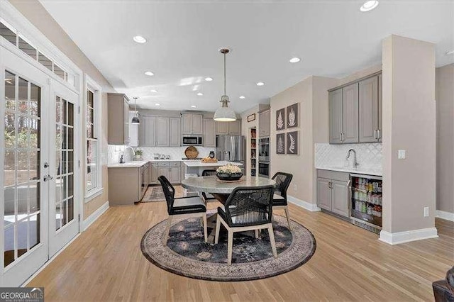 dining space featuring light wood-type flooring, recessed lighting, beverage cooler, french doors, and baseboards