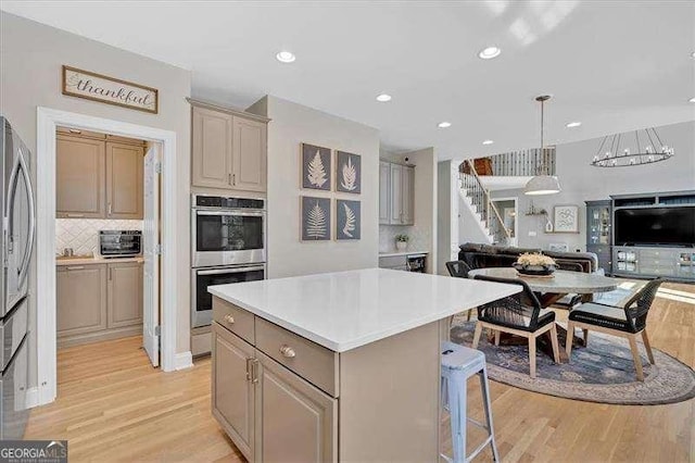 kitchen featuring open floor plan, double oven, a center island, and light wood finished floors
