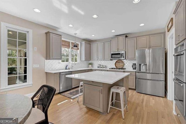 kitchen featuring light wood-style flooring, appliances with stainless steel finishes, gray cabinetry, and a breakfast bar