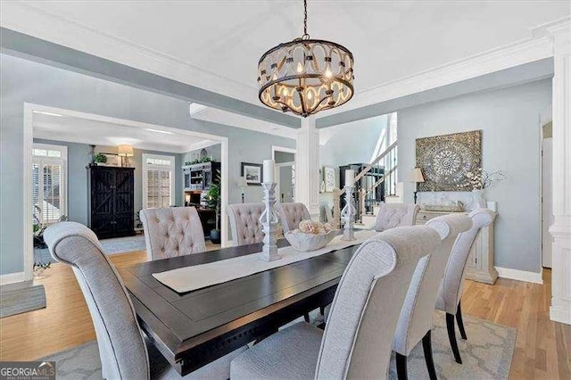 dining room with crown molding, baseboards, a chandelier, and light wood-style floors