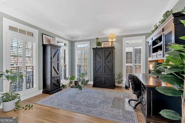 office featuring wood finished floors, ornamental molding, a barn door, and a wealth of natural light